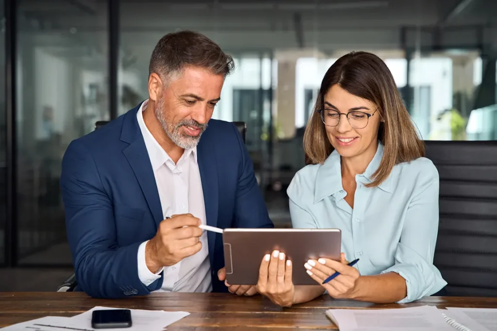Business professionals discussing LLC and Canadian business structure options on tablet in modern office setting