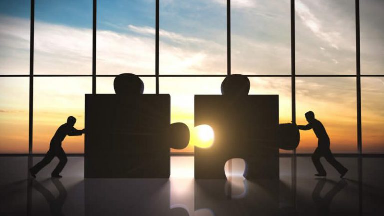 Business partners connecting puzzle pieces at sunset - adding partner to Ontario business registration