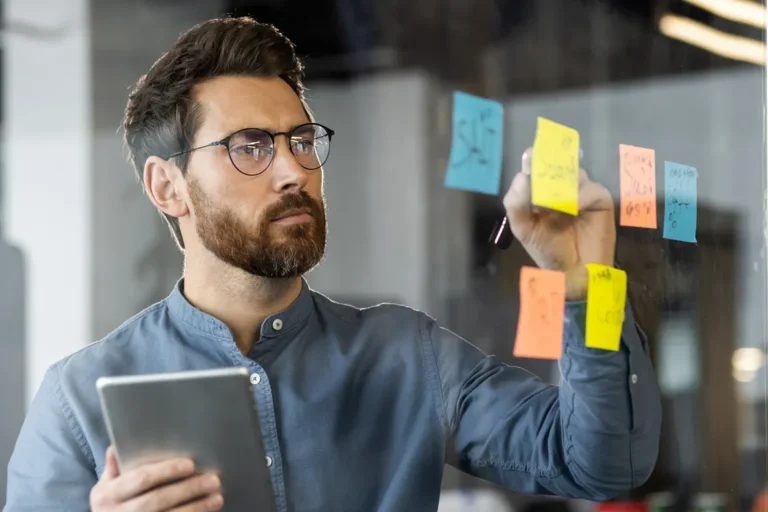 Business strategist planning corporation name change process using sticky note organization and digital research tools