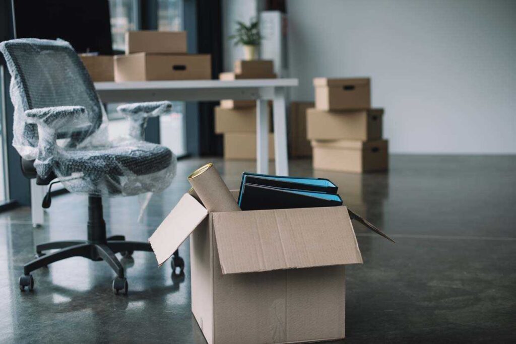 Office relocation - packed moving boxes and wrapped office chair representing business address change requirements in Ontario