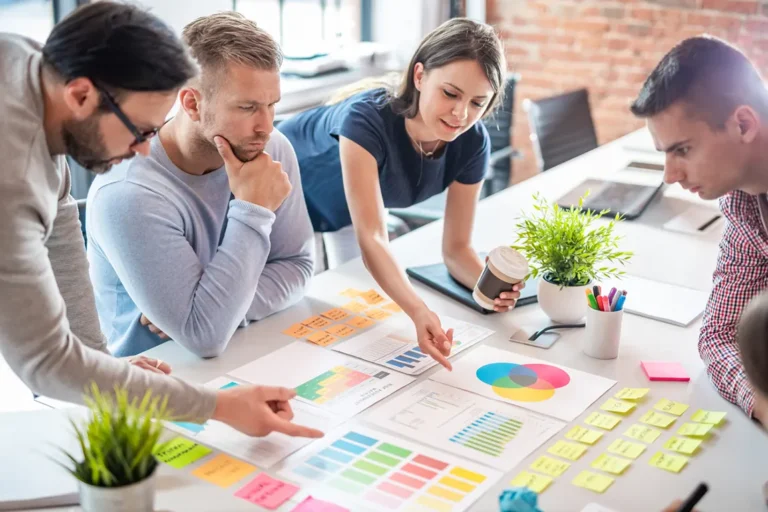 Business team collaborating on DBA (doing business as) name strategy with charts and marketing materials on conference table