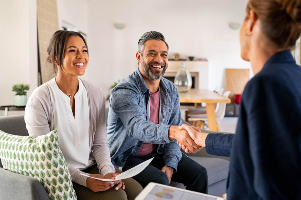 Happy couple shaking hands with advisor holding documents - Ontario guide to free Canadian government business funding
