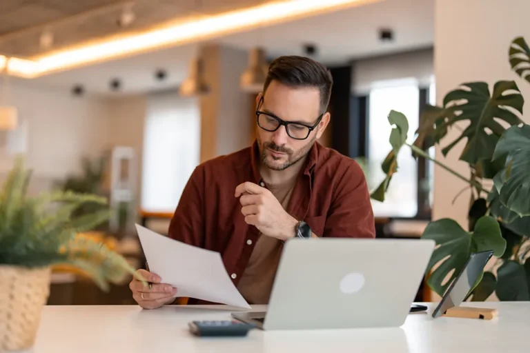 Professional businessman reviewing documents at laptop - understanding Ontario business numbers and BIN identification requirements