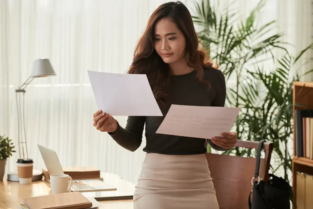 Professional businesswoman reviewing corporate documents and paperwork in modern office setting