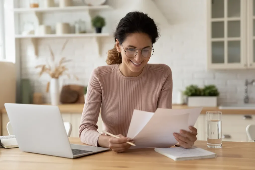 Home-based business owner reviewing corporate documents and laptop for QuickBooks profile integration