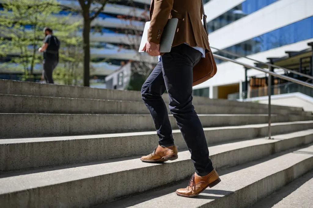 Professional businessman walking up steps with laptop and briefcase symbolizing steps to start new business in Ontario
