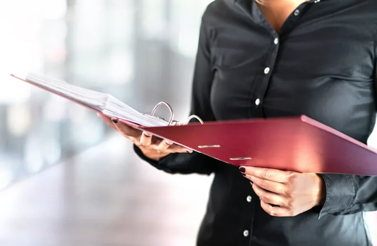 Business professional holding corporate minute book binder with company documents inside.