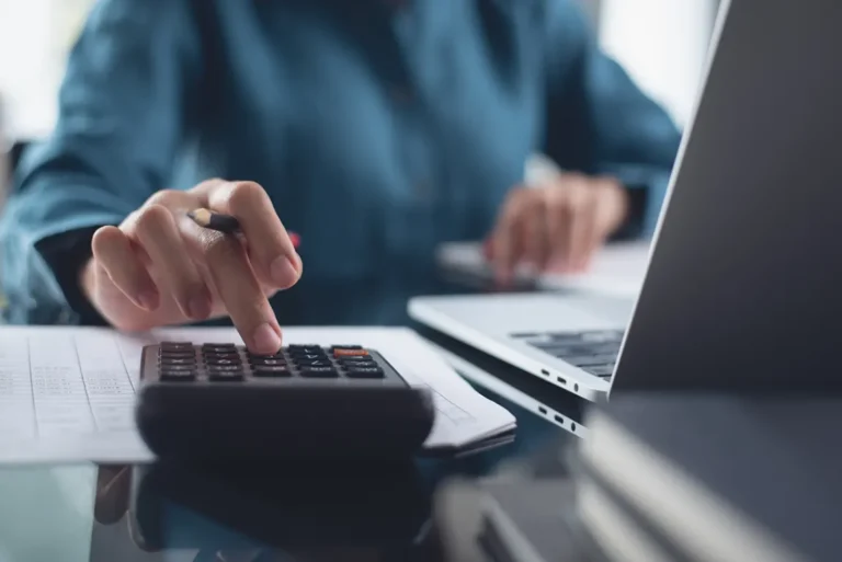 Beginner learning bookkeeping basics using calculator and laptop to track business finances and expenses