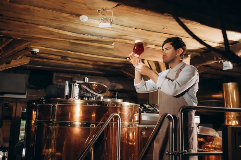 Craft brewer inspecting beer quality at copper brewing equipment in Ontario microbrewery requiring liquor license