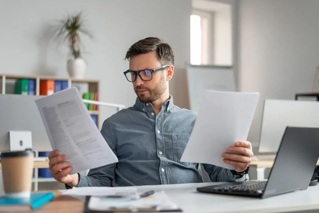 Professional examining annual corporate return paperwork and financial statements at workspace