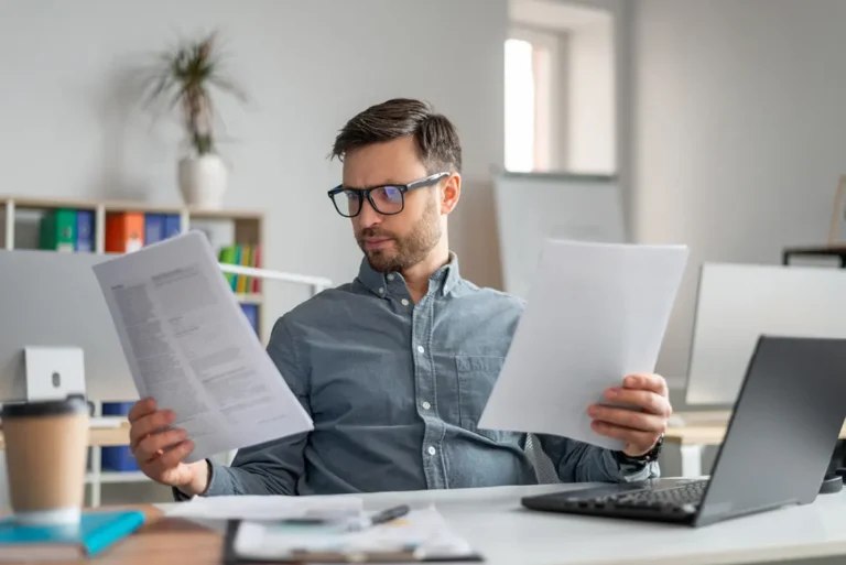 Professional examining annual corporate return paperwork and financial statements at workspace