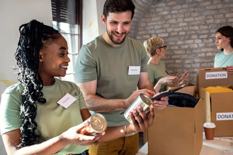 Diverse volunteers wearing name tags organizing donation boxes for nonprofit organization in Canada
