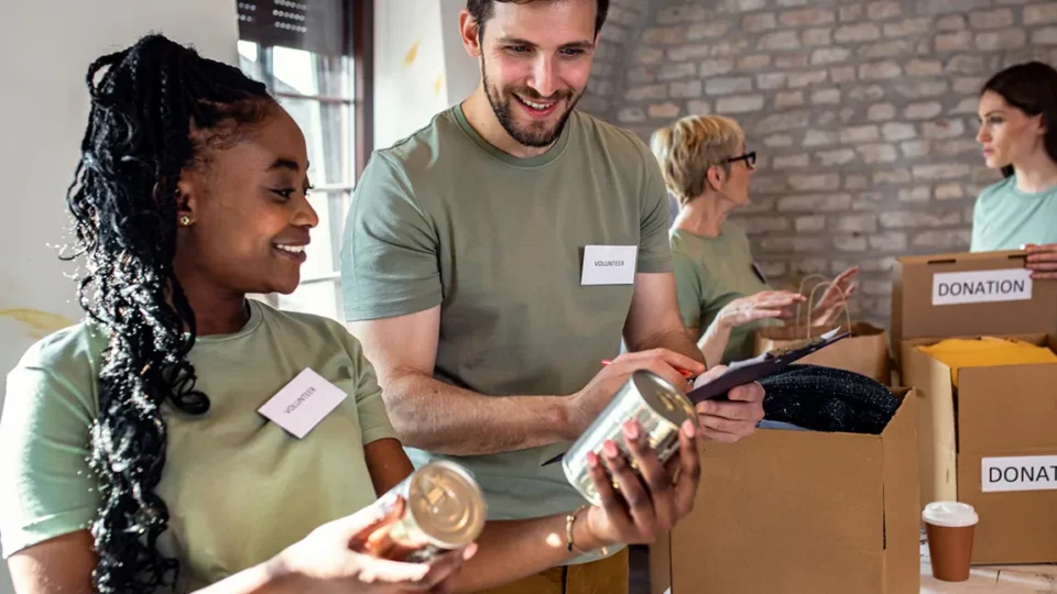 Diverse volunteers wearing name tags organizing donation boxes for nonprofit organization in Canada