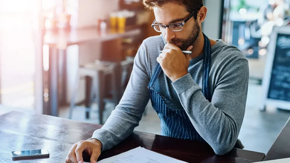 Small business owner carefully reviewing incorporation paperwork and legal documents at cafe