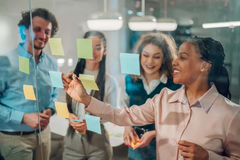 A group of business professionals brainstorming ideas for a new company name in a modern office setting.