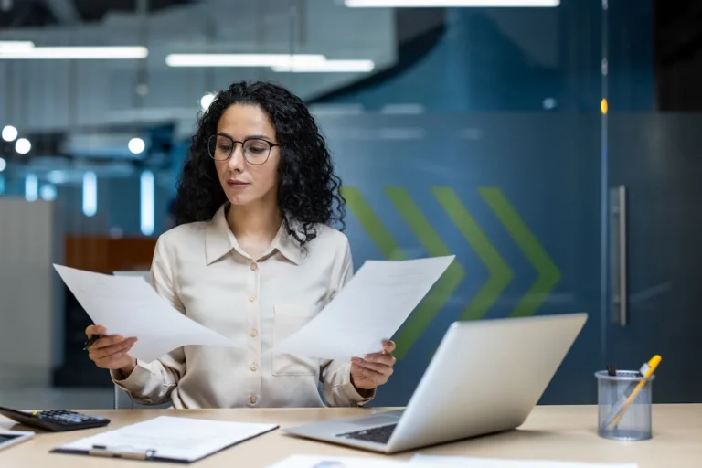 A woman examines documents at her desk, comparing a business registration with a business license.