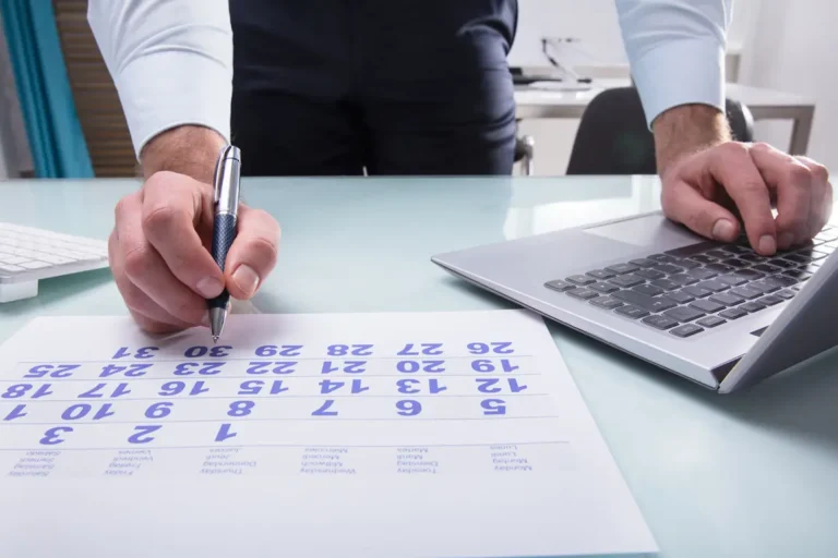 A man is writing on a calendar, verifying if his corporation needs to be renewed.
