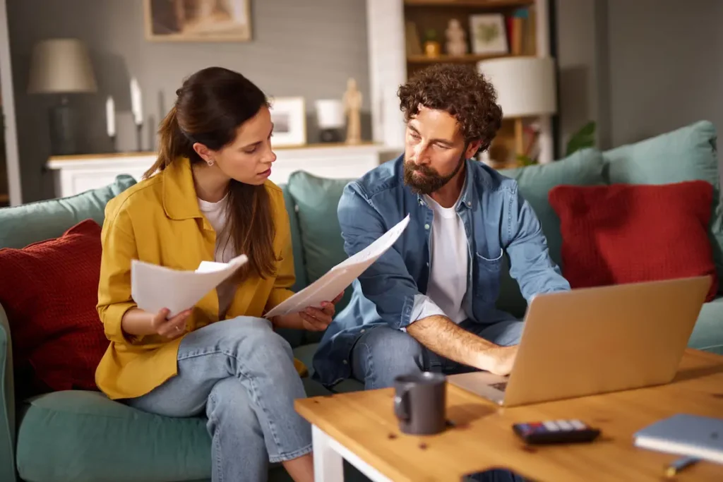 A man and woman sitting on a couch, reviewing paperwork for incorporating a business in Ontario.