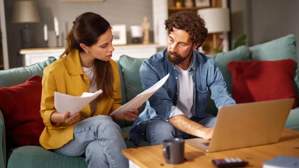 A man and woman sitting on a couch, reviewing paperwork for incorporating a business in Ontario.