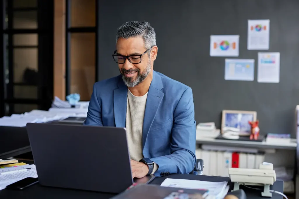 A man in a suit works on his laptop, analyzing the differences between sole proprietorship and incorporation.