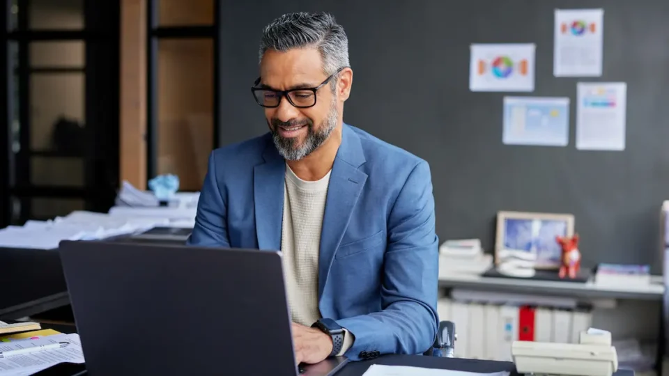 A man in a suit works on his laptop, analyzing the differences between sole proprietorship and incorporation.