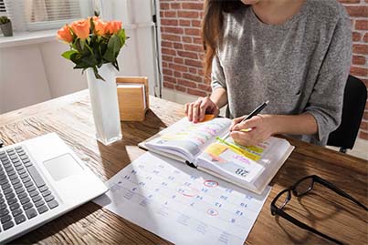 Businesswoman marking annual return filing deadline on a calendar and planner